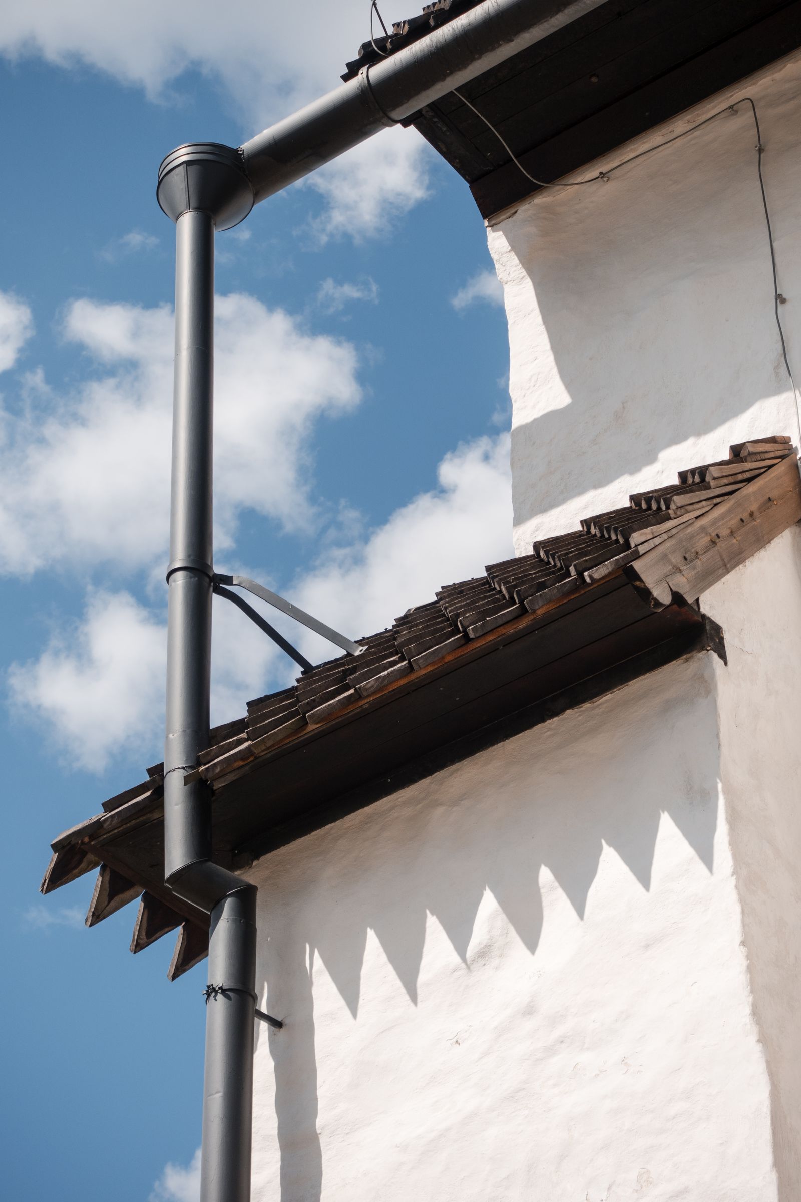 A gutter running along the eave of a house against an open sky